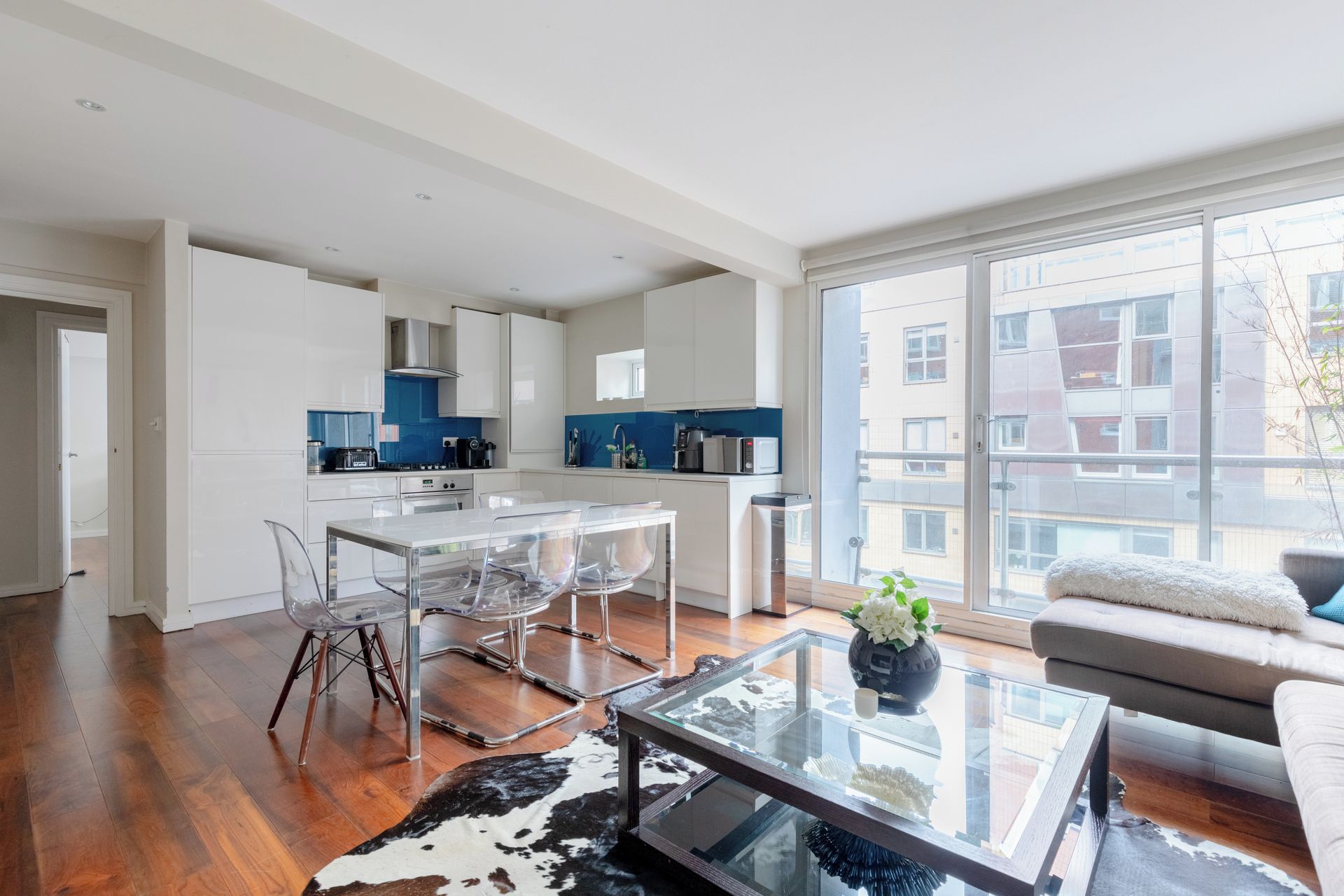 A modern kitchen with white cabinets, a blue backsplash, and stainless steel appliances.