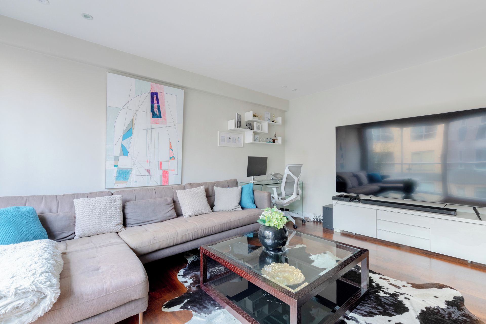 Een moderne woonkamer met een bank, salontafel en een flatscreen televisie.