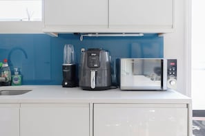 A kitchen with a coffee maker, a blender, and a microwave.