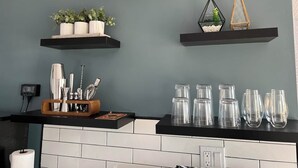 Uma cozinha com bancada preta, azulejos brancos e três prateleiras pretas.