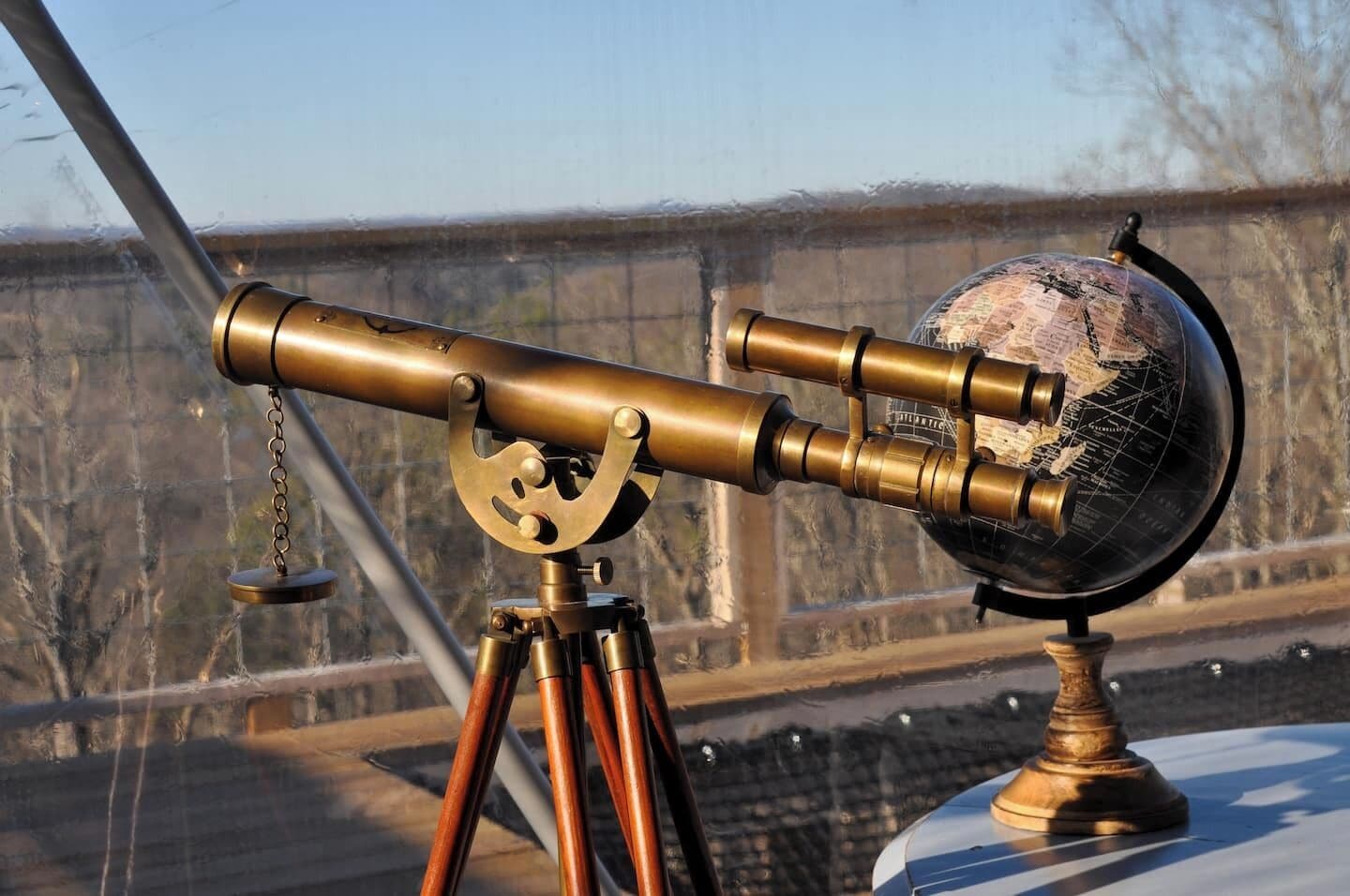 Een messing telescoop met een globe, geplaatst op een statief.