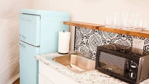 Uma cozinha compacta com geladeira azul claro, micro-ondas e painel decorado.