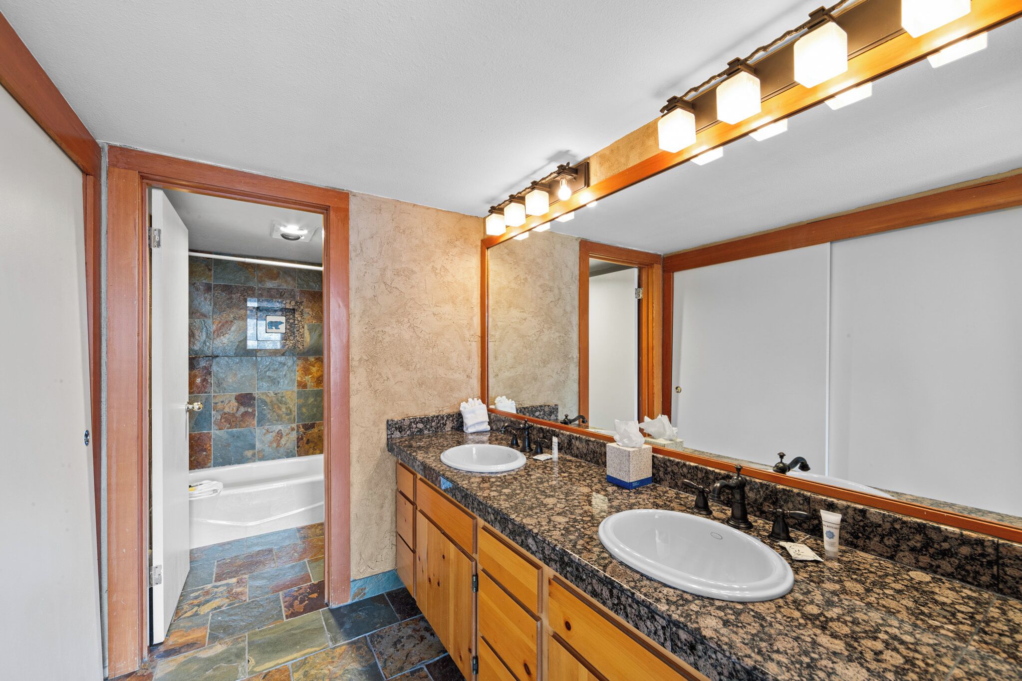 A bathroom with two sinks, a large mirror, and a shower.