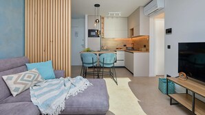 A modern living room with a sofa, a TV, and a kitchen in the background. - Hedera Estate, Hedera A44 (Dubrovnik)