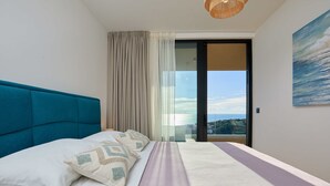 A bedroom with a large bed, a view of the sea through a glass door, and a painting on the wall. - Hedera Estate, Hedera A44 (Dubrovnik)