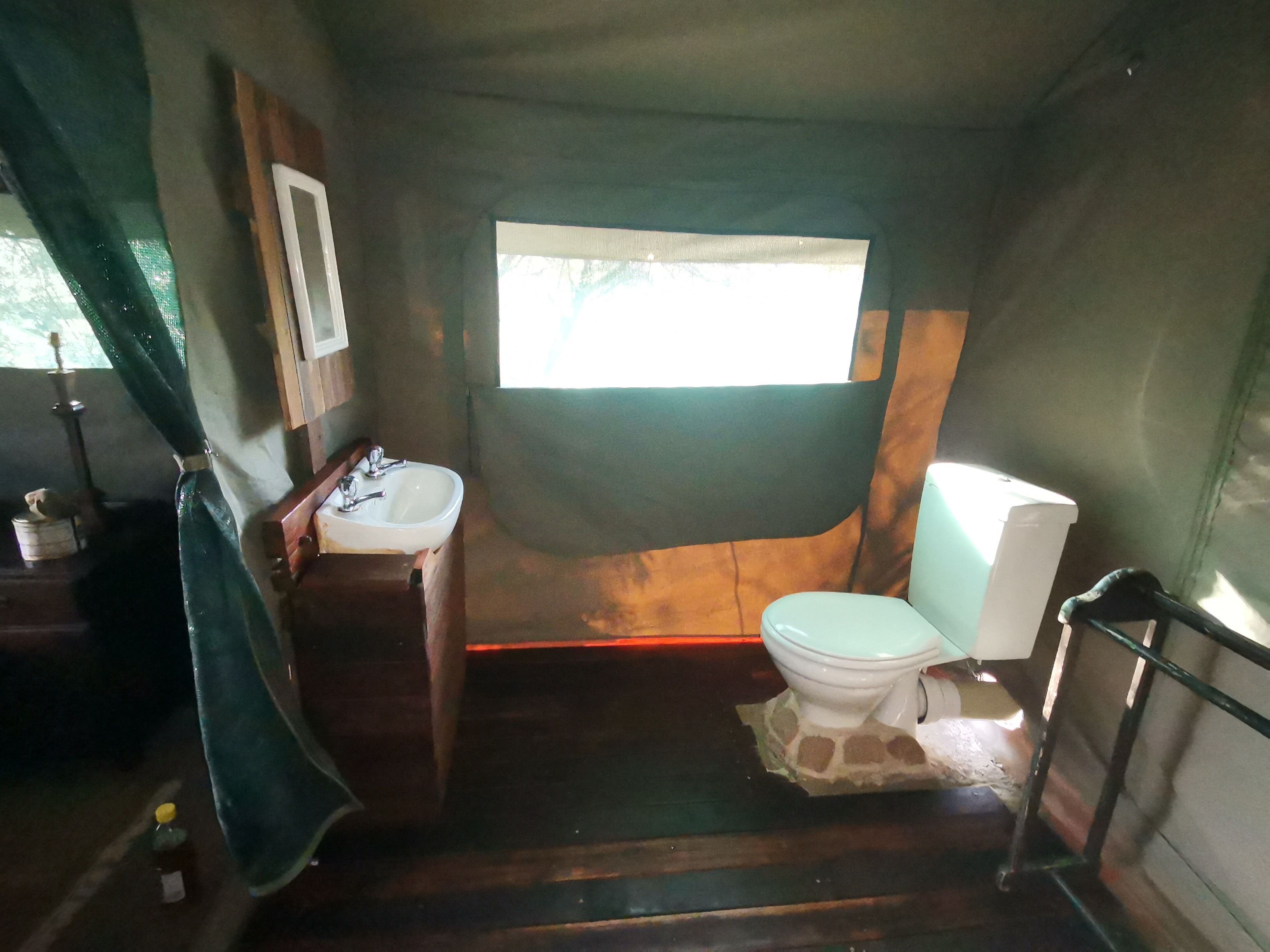 Une petite salle de bain comprenant un lavabo, des toilettes et une petite fenêtre pour laisser entrer la lumière naturelle.