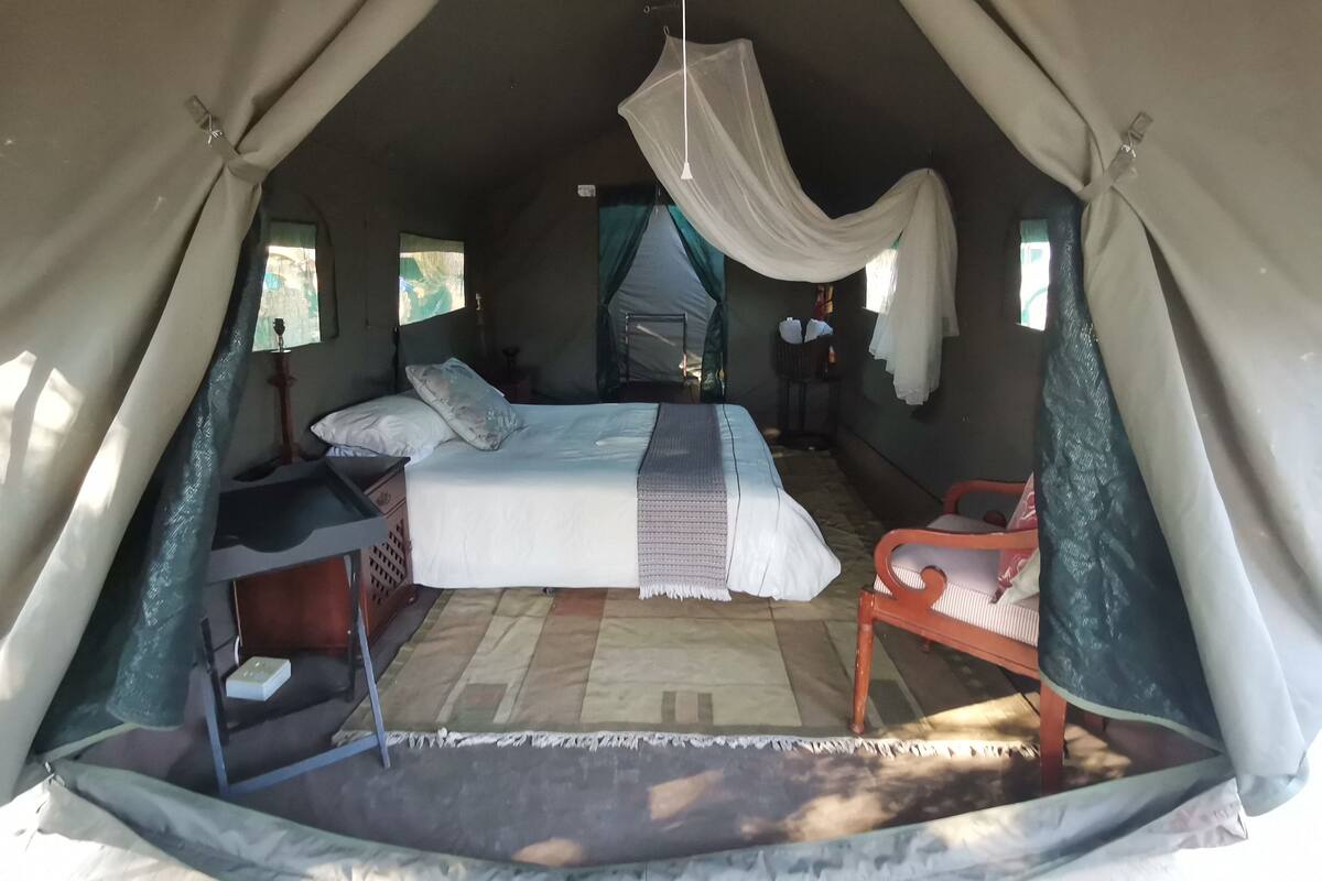 A tent-style room with a bed, a chair, and a small table.