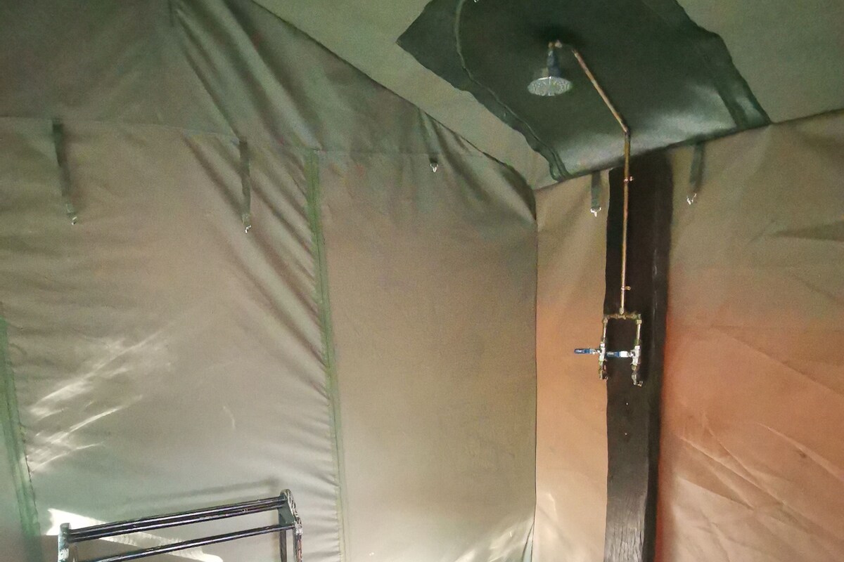 A tent with a metal bed frame, a white mattress, and a small window.