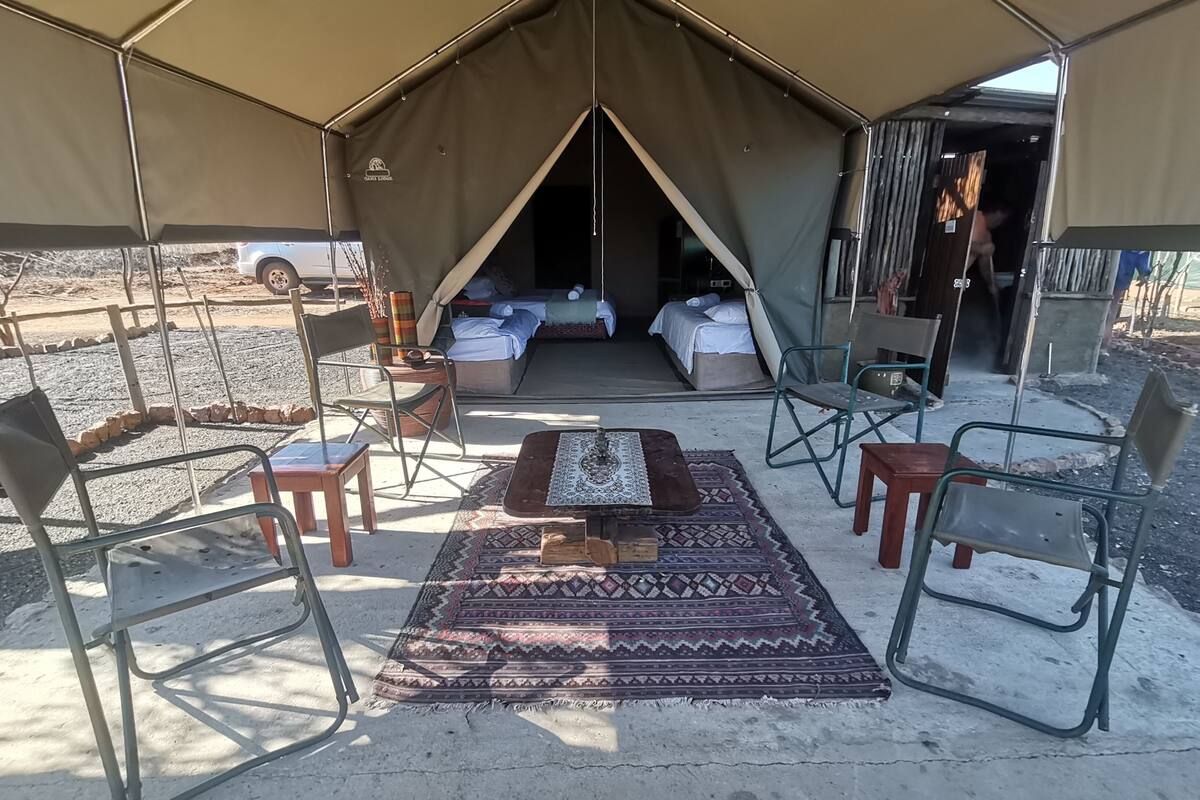 A tent with a bed, a table, and chairs arranged inside.