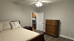 Une chambre à coucher avec un lit, une commode en bois et un ventilateur de plafond.