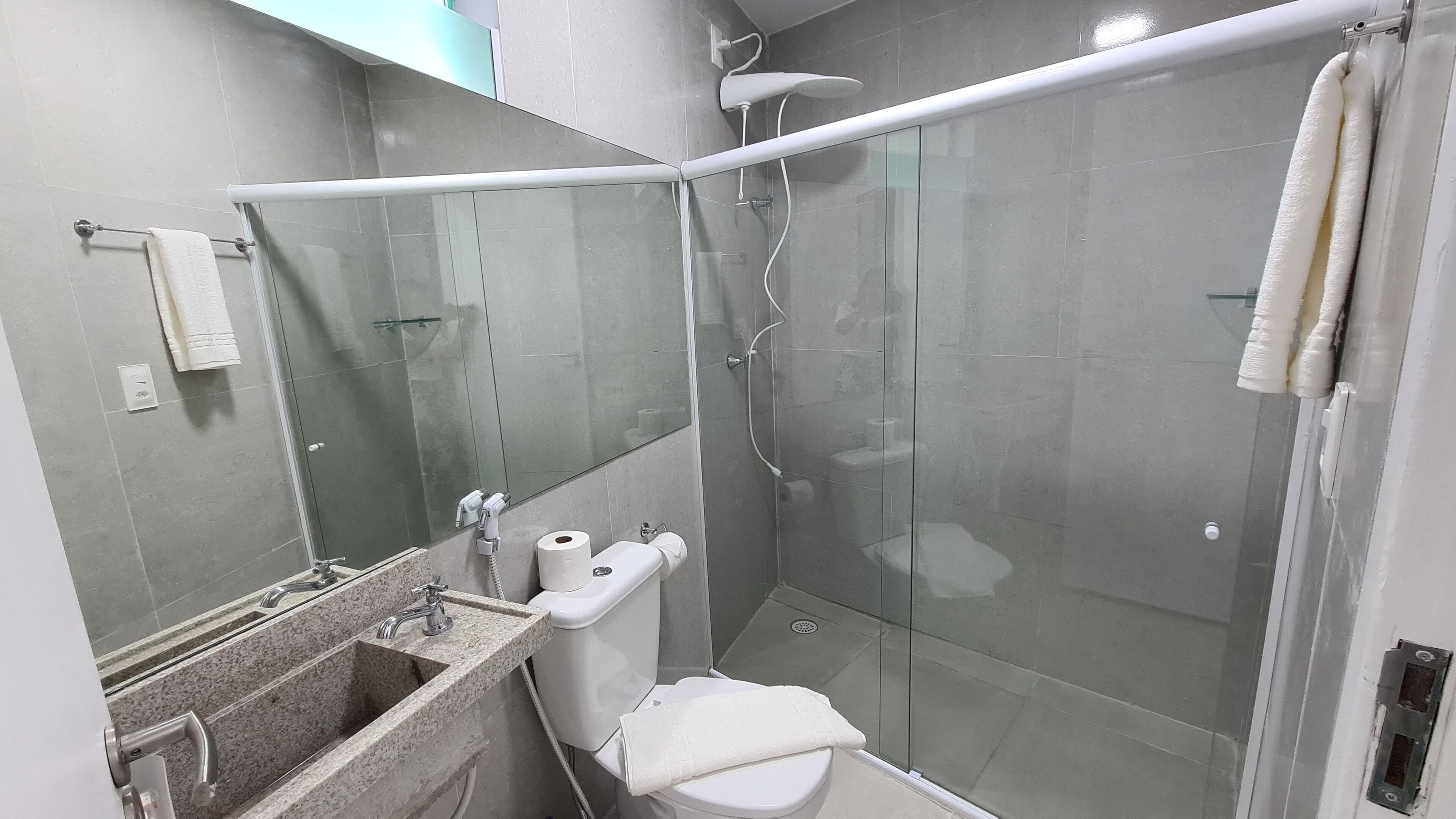 A modern bathroom with a glass shower enclosure, a sink with a marble countertop, and a toilet.