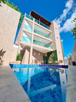A modern hotel with a pool, multiple balconies, and outdoor seating. - Sunset by AFT - Porto de Galinhas (Ipojuca)