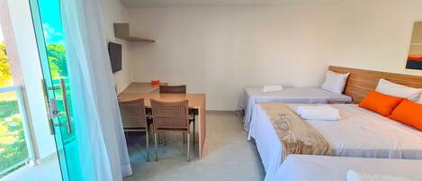 Habitación de hotel con comedor, dos camas y televisor.