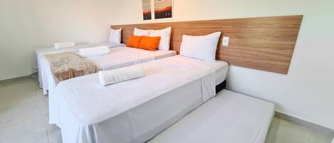 Une chambre d’hôtel avec deux lits simples, chacun doté de draps blancs et d’un plaid marron. On y trouve une tête de lit en bois et une œuvre d’art accrochée au mur, représentant un coucher de soleil.