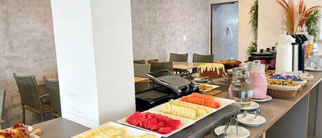 A buffet with various food items including meats, fruits, and beverages.