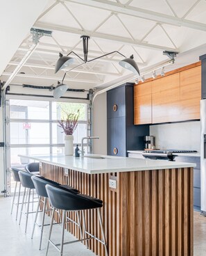 A modern kitchen with a central island, bar stools, and wooden cabinetry.