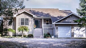 Ein zweigeschossiges Haus mit Veranda, Garage und kleinem Vorgarten mit Schotterauffahrt.