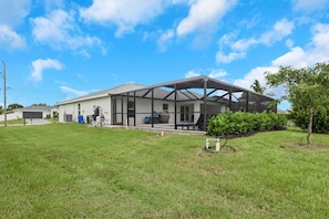 A residential house with a covered patio, a garage, and a well-maintained lawn.