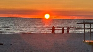 A sunset over the ocean with people on the beach. - New Build W/ Heated Pool! Perfect for 2 families! (Cape Coral)