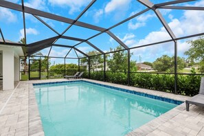 An indoor swimming pool with a clear view of the sky and surrounding greenery.