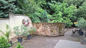 Ein Innenhof mit Steinmauern, Blumentöpfen und einem Metallgitter.