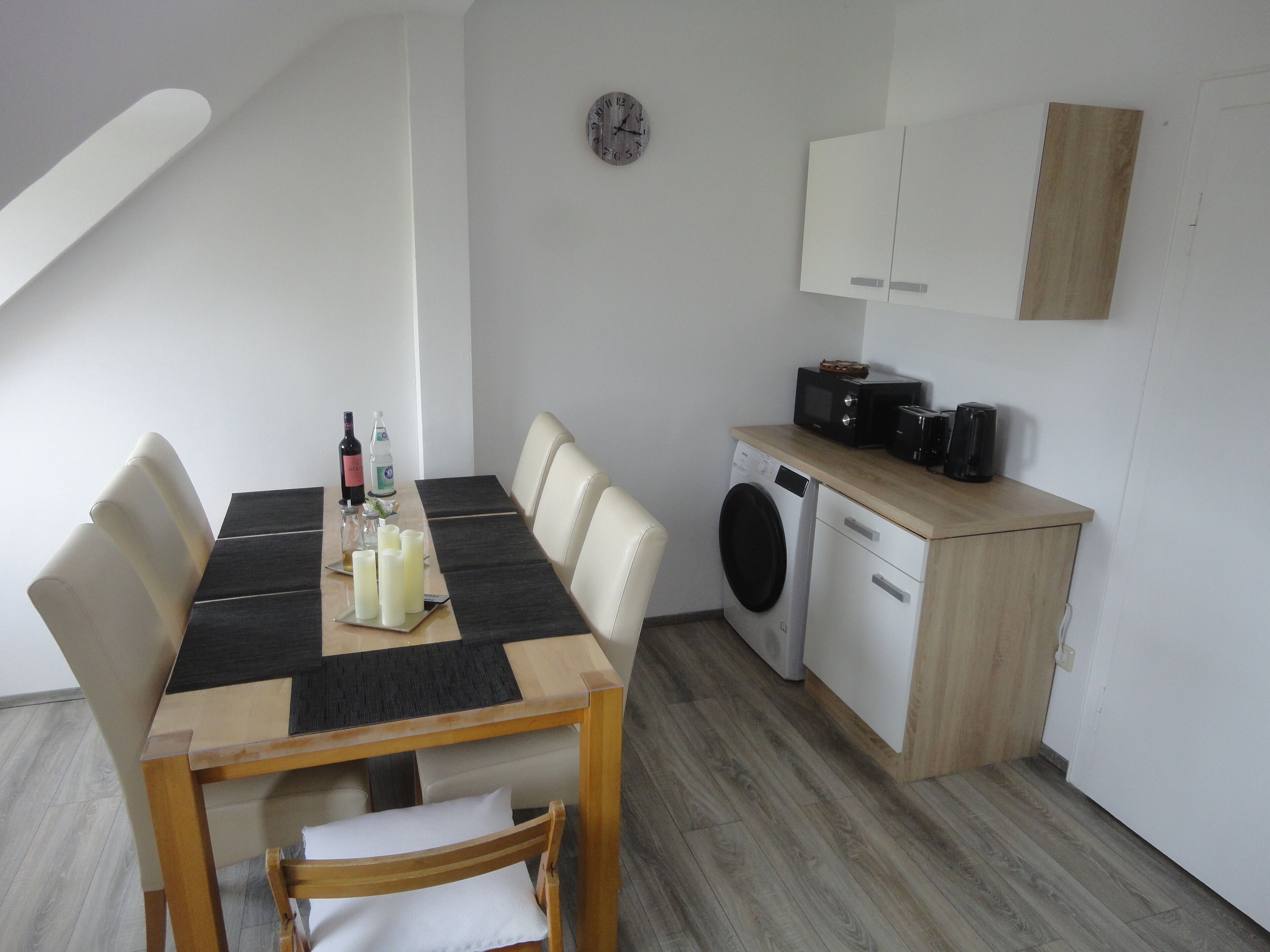 A compact kitchen with a dining area, including a microwave, toaster, and washing machine.