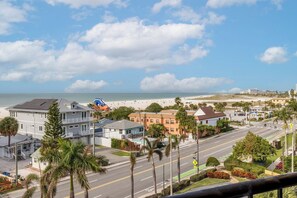 A coastal town with a beach, residential buildings, and a road with a pedestrian crossing.