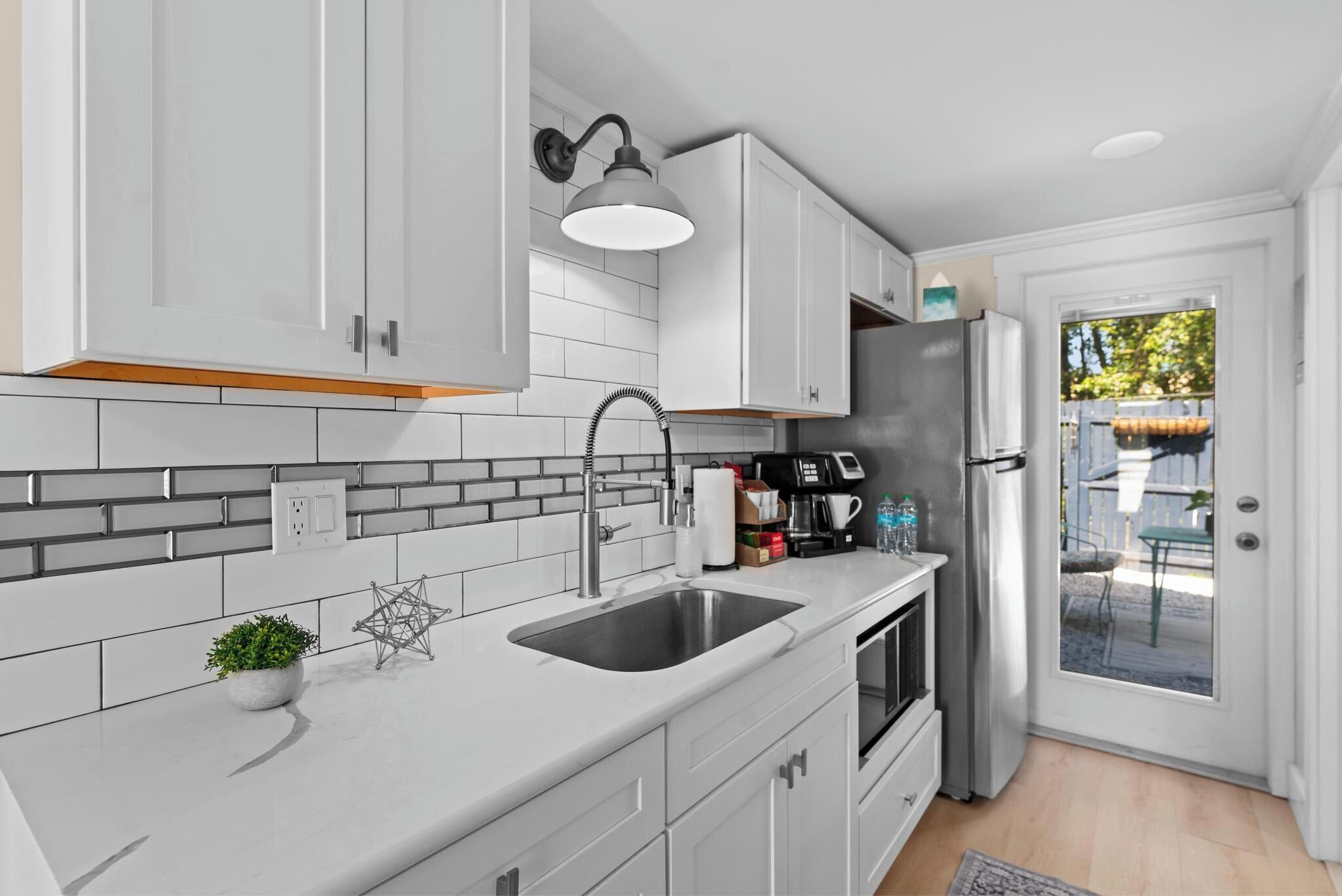A modern kitchen with white cabinets, a stainless steel sink, and a built-in oven.
