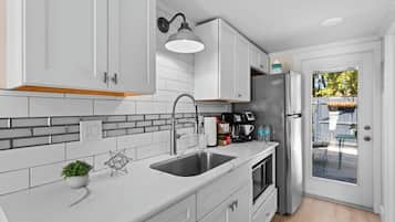 A modern kitchen with white cabinets, a stainless steel sink, and a built-in oven.