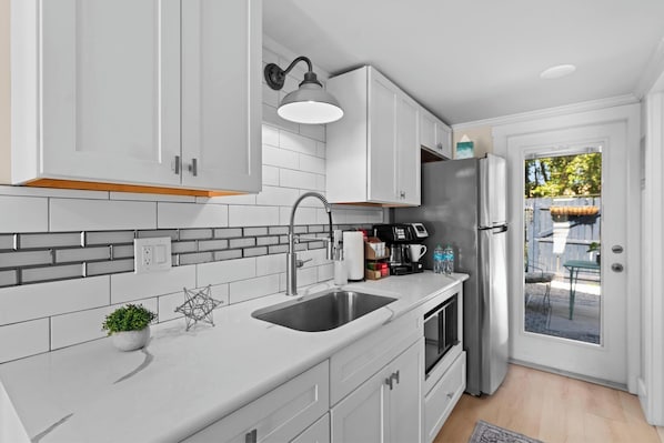 A modern kitchen with white cabinets, a stainless steel sink, and a built-in oven.