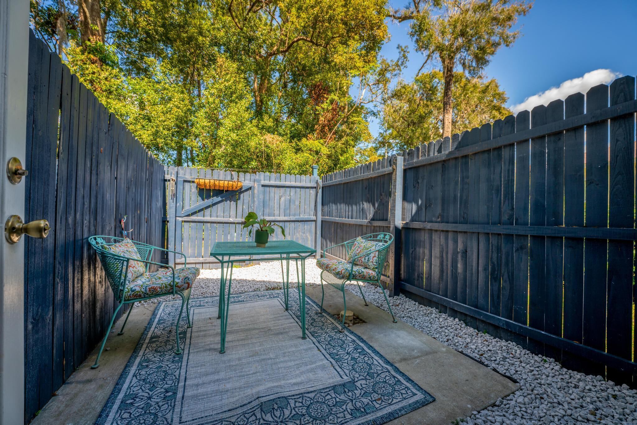 A patio with a table and chairs, surrounded by a wooden fence and trees.