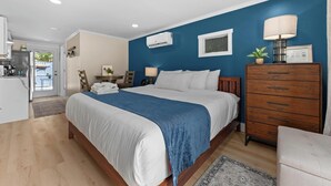 Une chambre à coucher comprenant un lit, une commode, une lampe et un appareil de climatisation.
