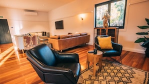 Una sala de estar moderna con un sofá de cuero, un sillón de cuero negro y una mesa de centro de madera.