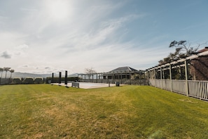 Un patio trasero cuidado con piscina, pérgola y vistas a montañas distantes.