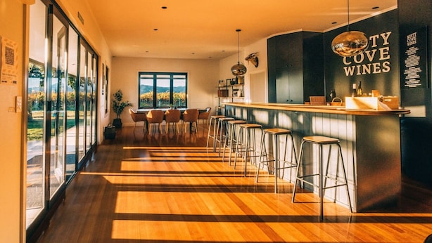 Zona de bar moderna con suelo de madera, taburetes y un letrero que dice "Misty Cove Wines".