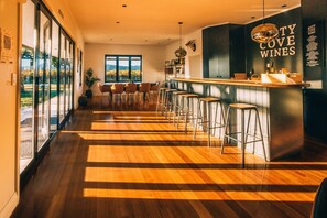 Un espace bar moderne avec un plancher en bois, des tabourets de bar et une enseigne indiquant « Misty Cove Wines ».