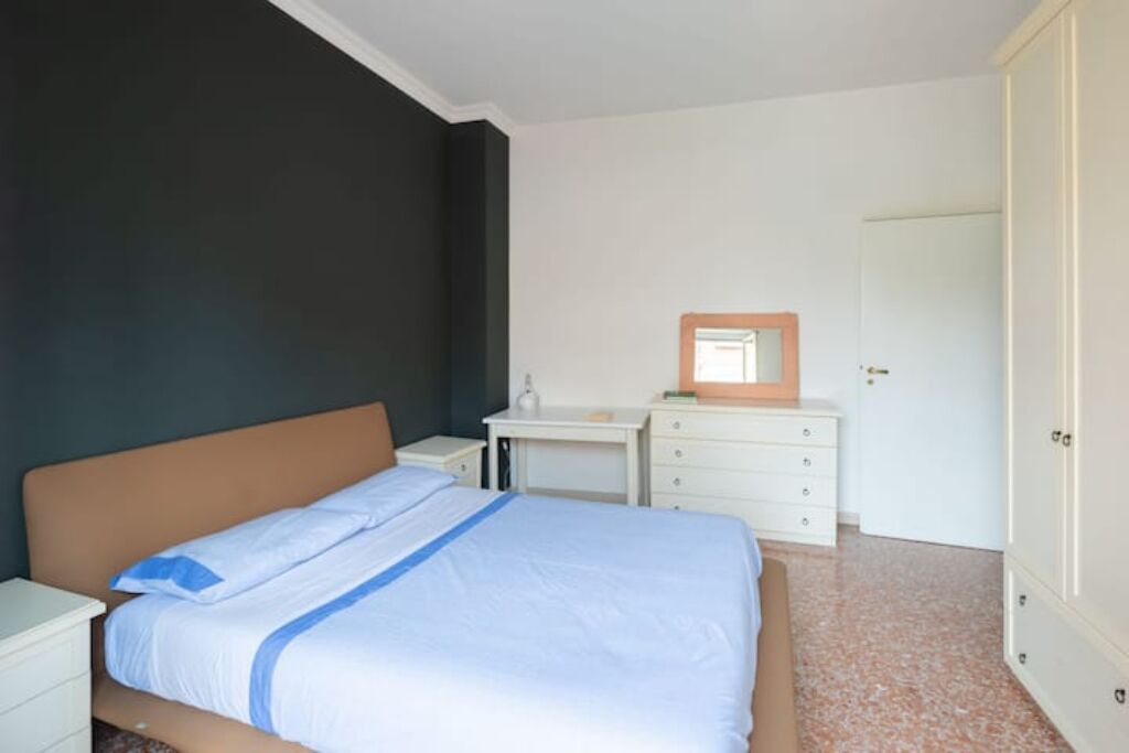 A bedroom with a bed, a nightstand, a dresser, and a door.