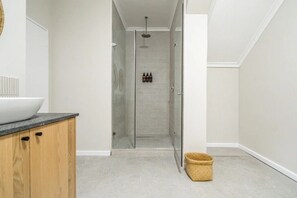 Bathroom features a large vessel sink, glass shower enclosure, and wooden cabinets.