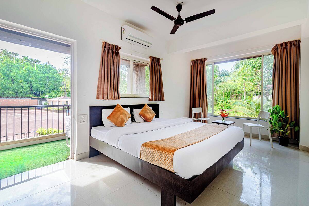 A hotel room with a large bed, a ceiling fan, and a view of the outdoors.