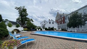 A swimming pool with lounge chairs and a paved patio area.
