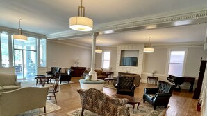 A spacious living room with hardwood floors, a large round coffee table, and several armchairs.