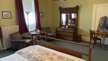 Une pièce comprenant un lit, une commode en bois, une chaise, une petite table et un miroir.