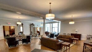 A spacious living room with a large sofa, armchairs, and a coffee table. There are multiple pendant lights and a fireplace.