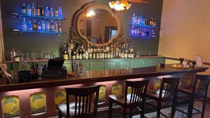 A bar area with a wooden counter, multiple liquor bottles, and bar stools.