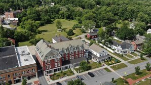 A residential area with a mix of single-family homes and a large brick building, likely a school or community center, surrounded by lush greenery.