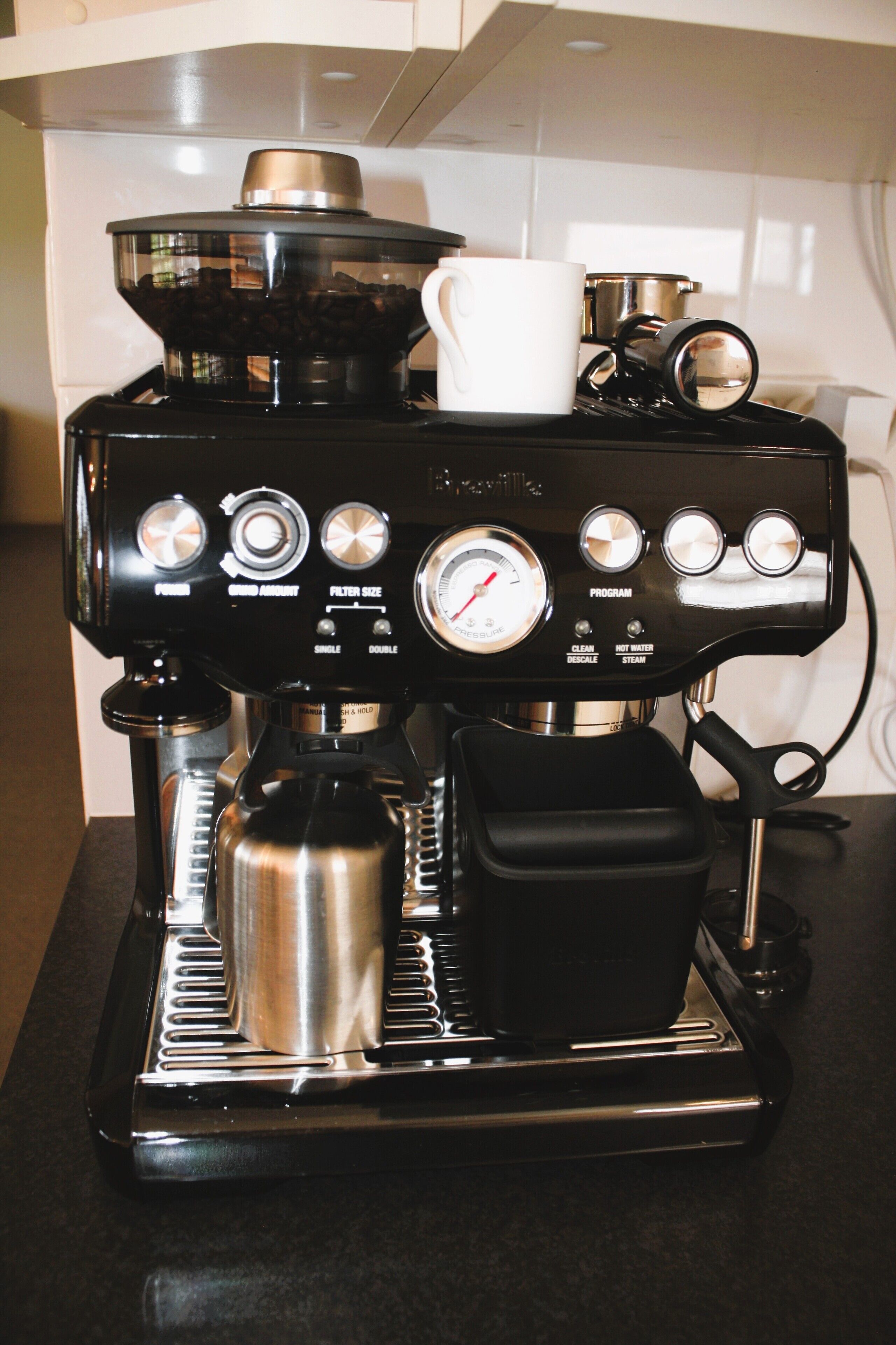 A coffee machine with a digital display, a milk frother, and a grinder.