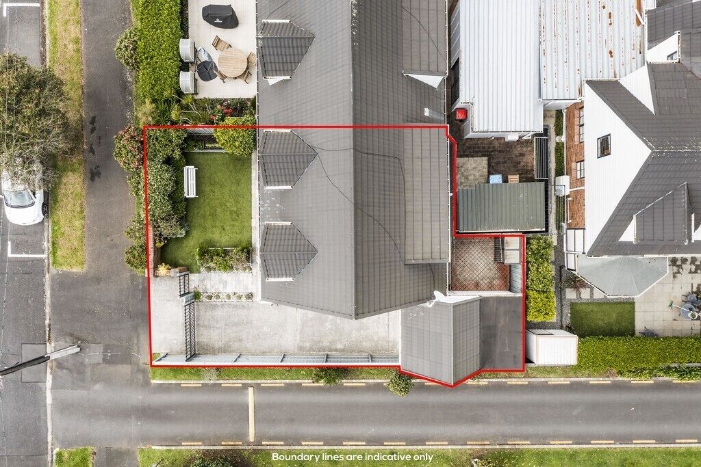 An aerial view of a residential property with a fenced yard, a detached garage, and a house with a sloped roof.