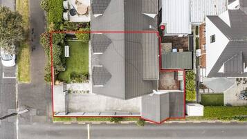 An aerial view of a residential property with a fenced yard, a detached garage, and a house with a sloped roof.