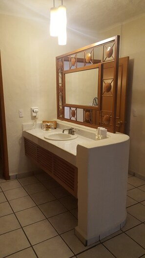 Bathroom features a double sink vanity with a large mirror and decorative frame, along with a towel and soap dispenser.