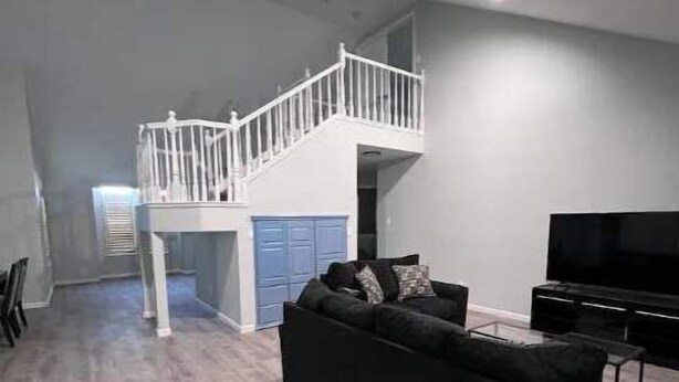 Un vaste espace de vie comprenant un canapé noir, un téléviseur et un escalier menant à un niveau supérieur.